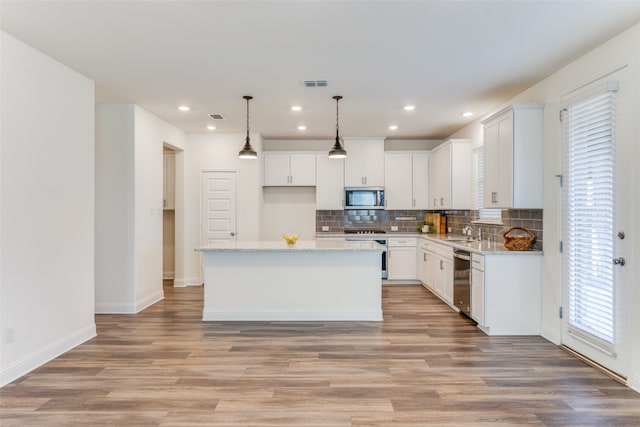 kitchen featuring appliances with stainless steel finishes, white cabinetry, a center island, and light hardwood / wood-style floors