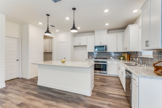 kitchen with dark hardwood / wood-style floors, white cabinets, a center island, and stainless steel appliances