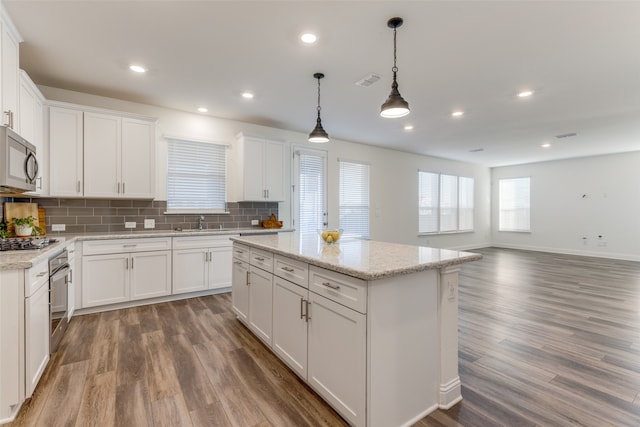 kitchen featuring white cabinets, light stone counters, dark hardwood / wood-style flooring, decorative light fixtures, and stainless steel appliances