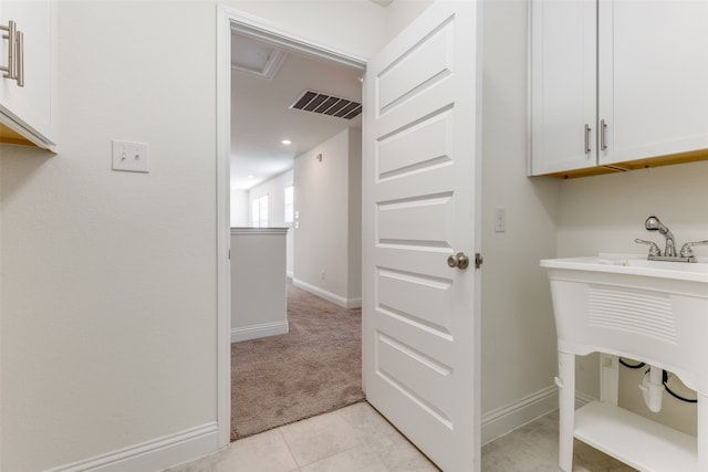 washroom with cabinets, light tile patterned flooring, and sink