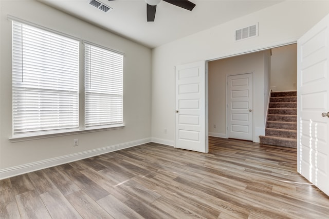 interior space with a closet, ceiling fan, multiple windows, and light wood-type flooring