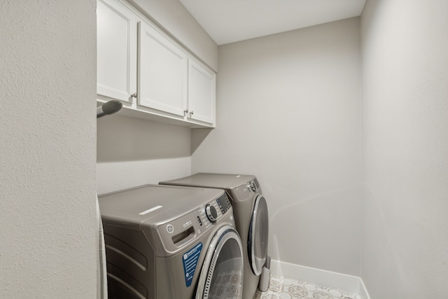 clothes washing area with cabinets and washer and clothes dryer