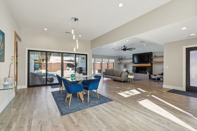 dining area with hardwood / wood-style flooring, ceiling fan, and a fireplace