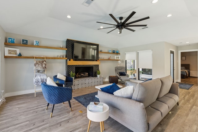 living room with a fireplace, ceiling fan, light hardwood / wood-style floors, and a tray ceiling