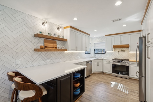 kitchen featuring stainless steel appliances, sink, white cabinetry, kitchen peninsula, and decorative backsplash