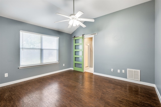 spare room featuring ceiling fan, vaulted ceiling, dark hardwood / wood-style flooring, and a barn door