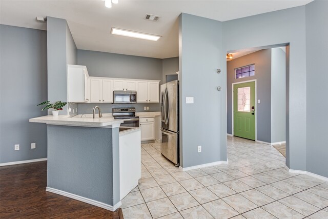 kitchen featuring kitchen peninsula, white cabinetry, light hardwood / wood-style flooring, sink, and stainless steel appliances