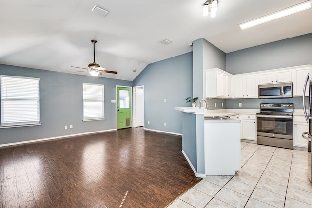 kitchen with appliances with stainless steel finishes, light wood-type flooring, kitchen peninsula, ceiling fan, and white cabinets