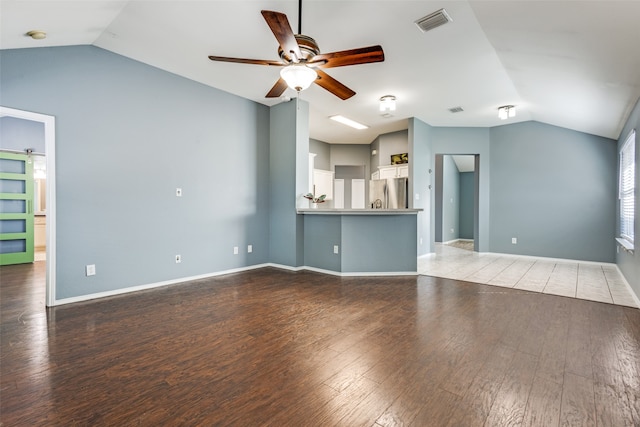 unfurnished living room featuring ceiling fan, hardwood / wood-style flooring, vaulted ceiling, and a barn door