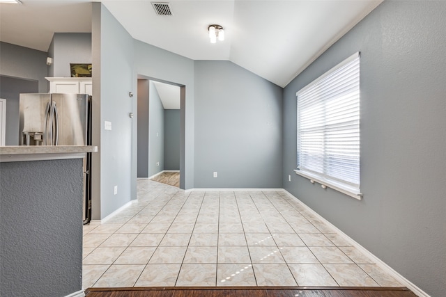 unfurnished room with lofted ceiling and light tile patterned floors