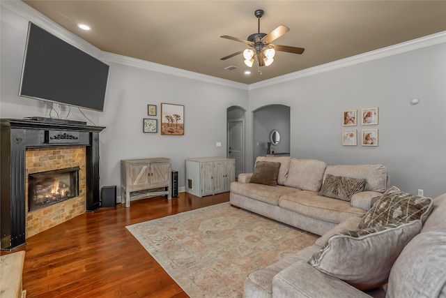 living room with ornamental molding, dark wood-type flooring, and ceiling fan