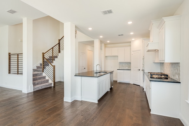 kitchen with sink, dark wood-type flooring, white cabinetry, and a kitchen island with sink