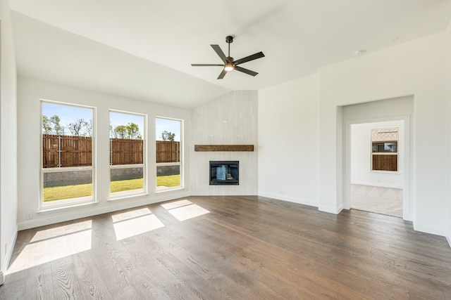 unfurnished living room with dark wood-type flooring, vaulted ceiling, a fireplace, and ceiling fan