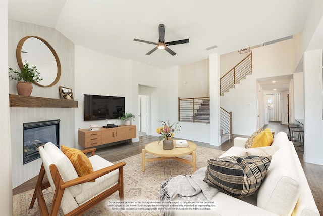 unfurnished living room with ceiling fan, high vaulted ceiling, a tile fireplace, and dark hardwood / wood-style floors