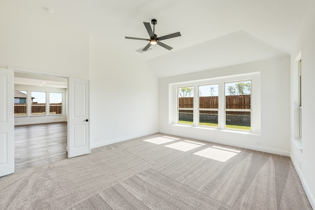 carpeted spare room with vaulted ceiling, ceiling fan, and plenty of natural light