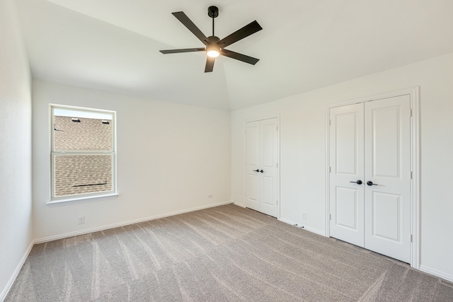 unfurnished bedroom with ceiling fan, multiple closets, lofted ceiling, and light colored carpet