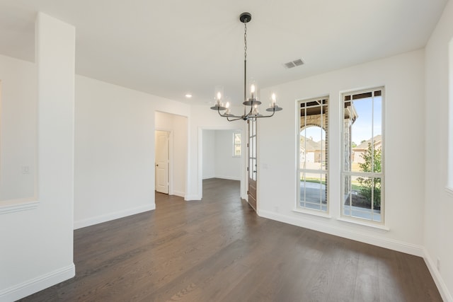 unfurnished dining area featuring dark wood-type flooring and a chandelier