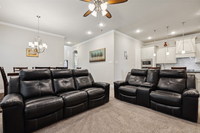 carpeted home theater featuring crown molding and ceiling fan with notable chandelier