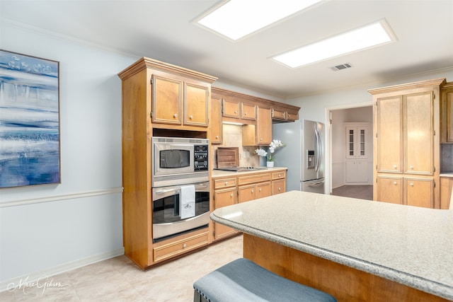 kitchen featuring crown molding, stainless steel appliances, light tile patterned floors, and backsplash