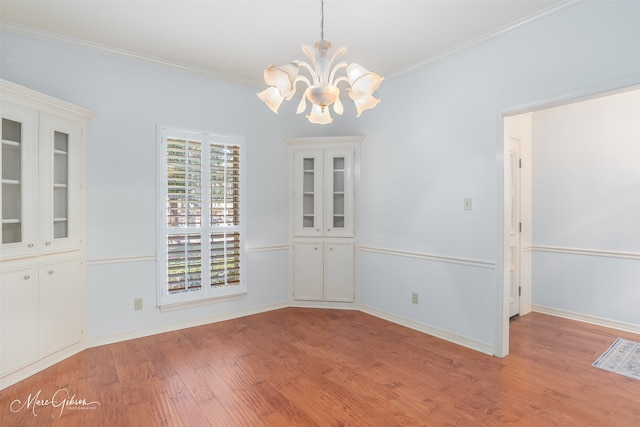 unfurnished dining area featuring ornamental molding, a chandelier, and light wood-type flooring