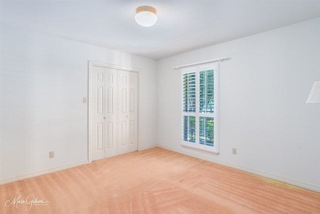 unfurnished bedroom featuring a closet and light colored carpet