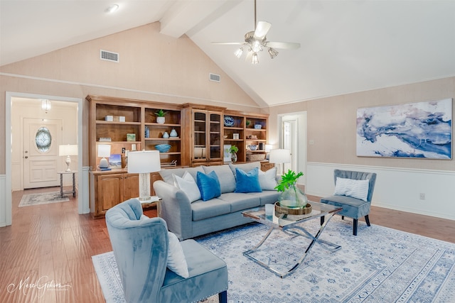 living room featuring beam ceiling, ceiling fan, high vaulted ceiling, light hardwood / wood-style flooring, and built in shelves