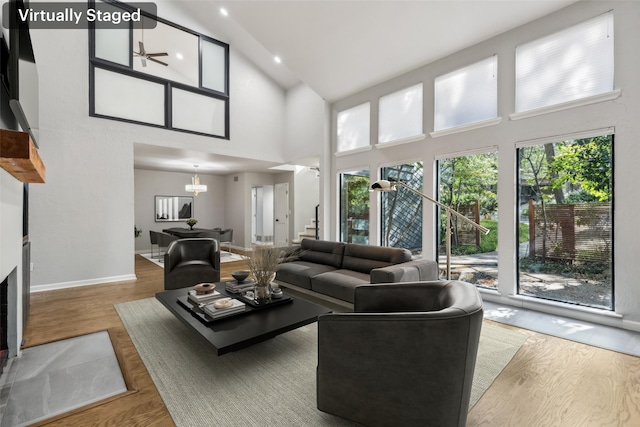 living room with hardwood / wood-style flooring, high vaulted ceiling, and ceiling fan with notable chandelier