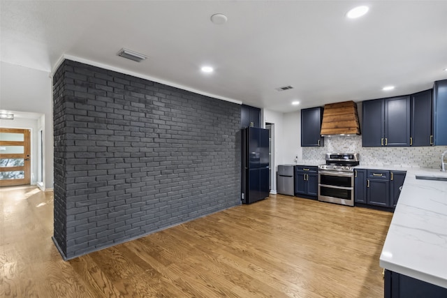 kitchen featuring black fridge, light hardwood / wood-style flooring, double oven range, custom exhaust hood, and light stone counters