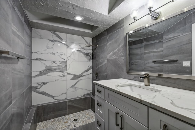 bathroom featuring tile walls, a tile shower, vanity, and decorative backsplash