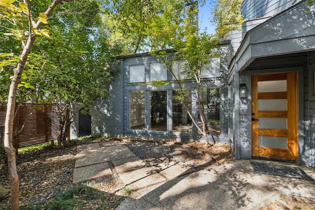 property entrance featuring fence and brick siding