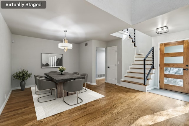 dining area with stairway, wood finished floors, visible vents, and baseboards