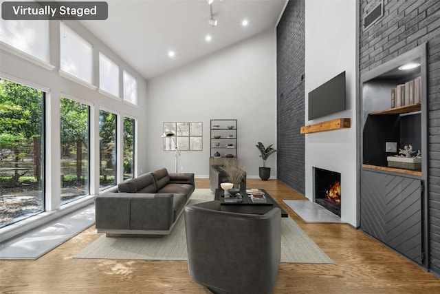 living area with a towering ceiling, a fireplace, baseboards, and wood finished floors