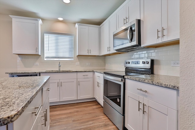 kitchen with white cabinetry, light hardwood / wood-style floors, appliances with stainless steel finishes, and sink