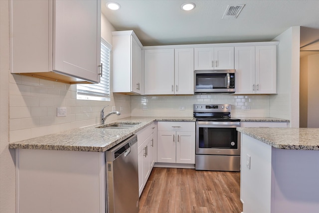 kitchen with sink, white cabinets, stainless steel appliances, and light wood-type flooring