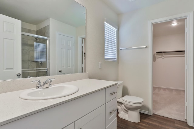 bathroom featuring vanity, hardwood / wood-style floors, walk in shower, and toilet