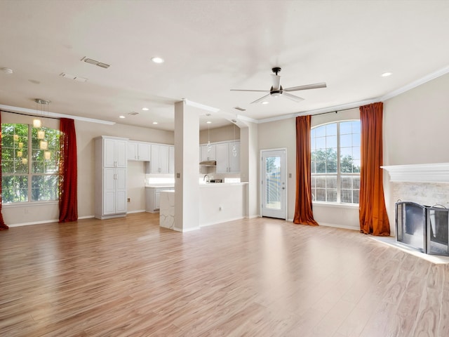 unfurnished living room with crown molding, a fireplace, ceiling fan, and light hardwood / wood-style floors