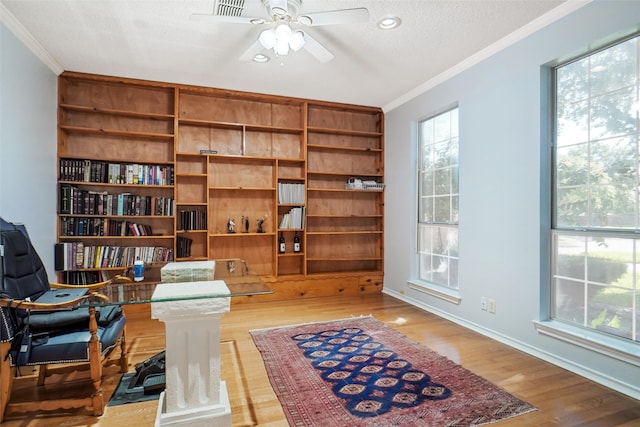 sitting room with crown molding, a textured ceiling, hardwood / wood-style flooring, and a healthy amount of sunlight