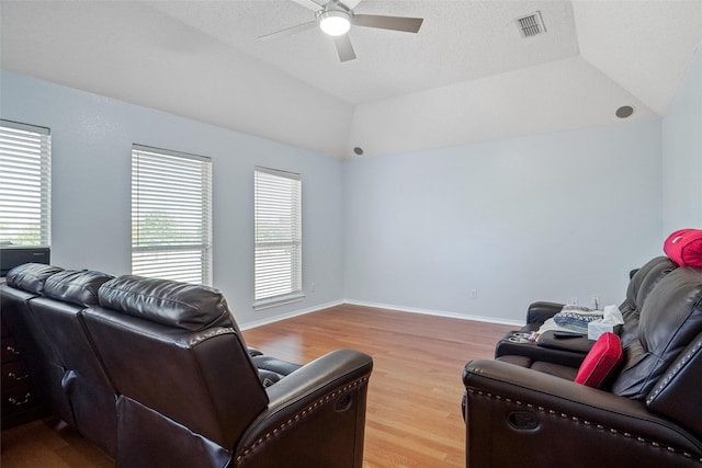 living room with ceiling fan, hardwood / wood-style flooring, a textured ceiling, and vaulted ceiling