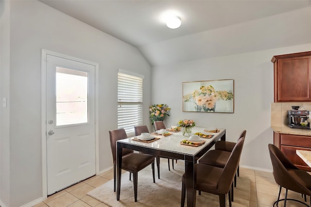 dining space with light tile patterned flooring and vaulted ceiling