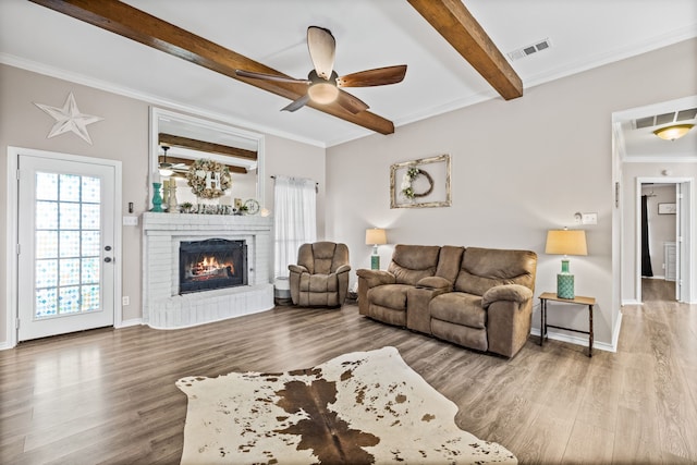 living room with beamed ceiling, hardwood / wood-style floors, a fireplace, and ceiling fan