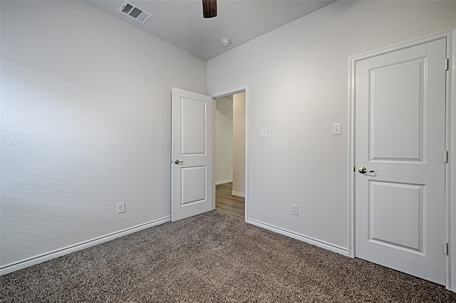 unfurnished bedroom with ceiling fan and dark colored carpet