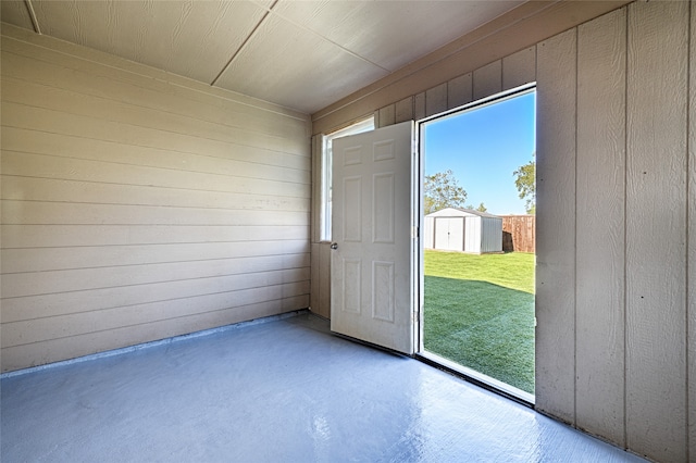 doorway featuring wooden walls and concrete flooring