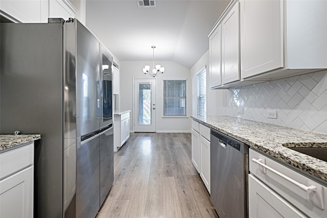 kitchen featuring lofted ceiling, appliances with stainless steel finishes, white cabinetry, light wood-type flooring, and light stone counters