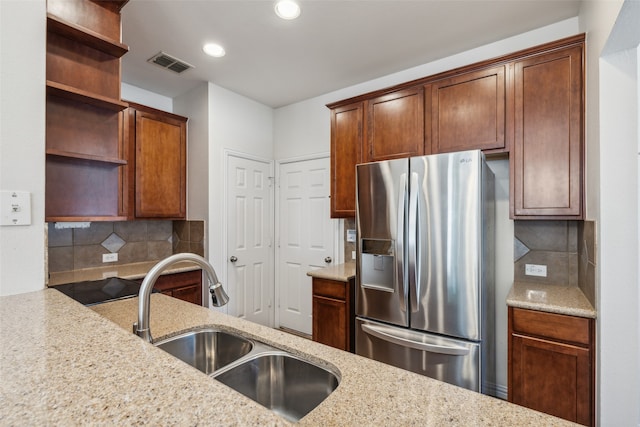 kitchen featuring sink, light stone counters, stainless steel refrigerator with ice dispenser, and tasteful backsplash