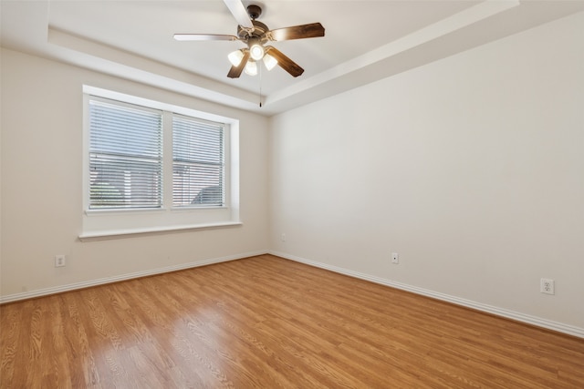 unfurnished room with light hardwood / wood-style floors, a tray ceiling, and ceiling fan