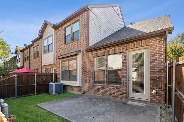 rear view of property with a yard, cooling unit, and a patio