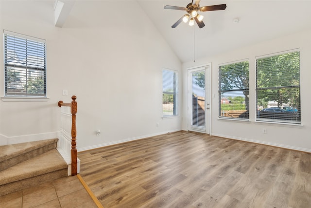 empty room featuring light hardwood / wood-style flooring, high vaulted ceiling, and ceiling fan