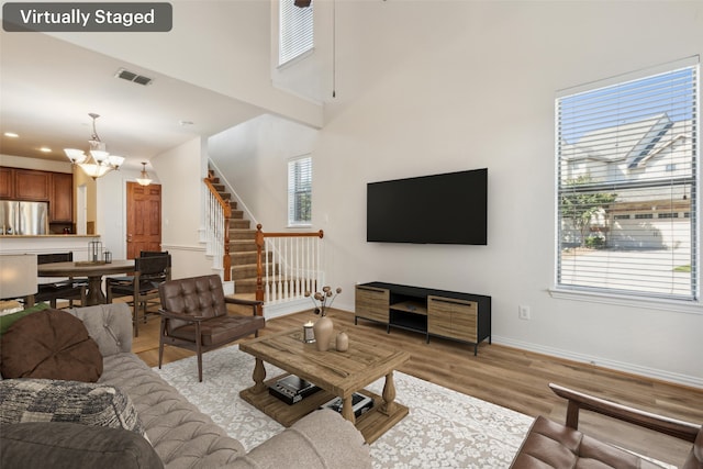 living room featuring a chandelier, a high ceiling, and light hardwood / wood-style floors