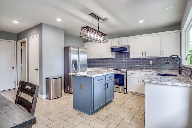 kitchen featuring a kitchen island, stainless steel appliances, sink, decorative light fixtures, and white cabinets