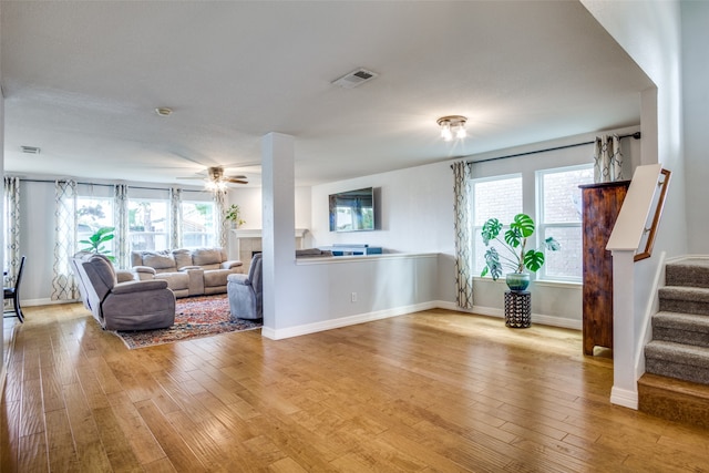 living room with light hardwood / wood-style flooring, a healthy amount of sunlight, a tiled fireplace, and ceiling fan